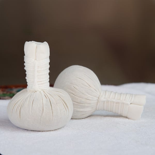 Setting with two cloths filled with poultice on a white towel. One is upright and the other is on its side.
