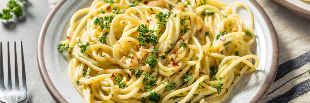Plate of creamy garlic pasta topped with herbs and spices