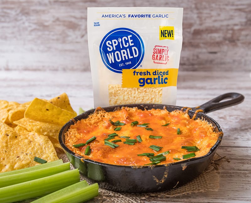 Package of diced garlic next to a skillet of cheesy dip and tortilla chips, suggesting a recipe