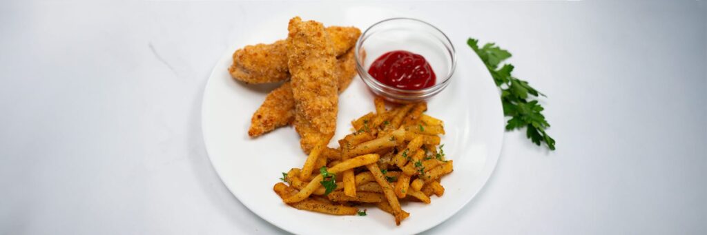 Plate of crispy chicken tenders and seasoned fries with a side of ketchup
