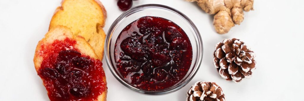 Sliced bread with homemade berry jam and ginger on a white background