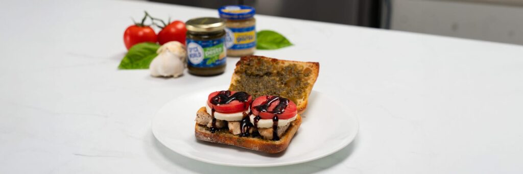 Caprese-style toasted bread with tomatoes, cheese, and balsamic glaze, presented on a white plate