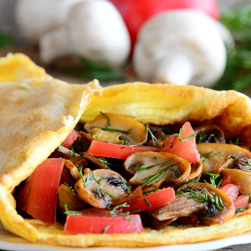 Savory crepe filled with mushrooms, tomatoes, and herbs on a plate