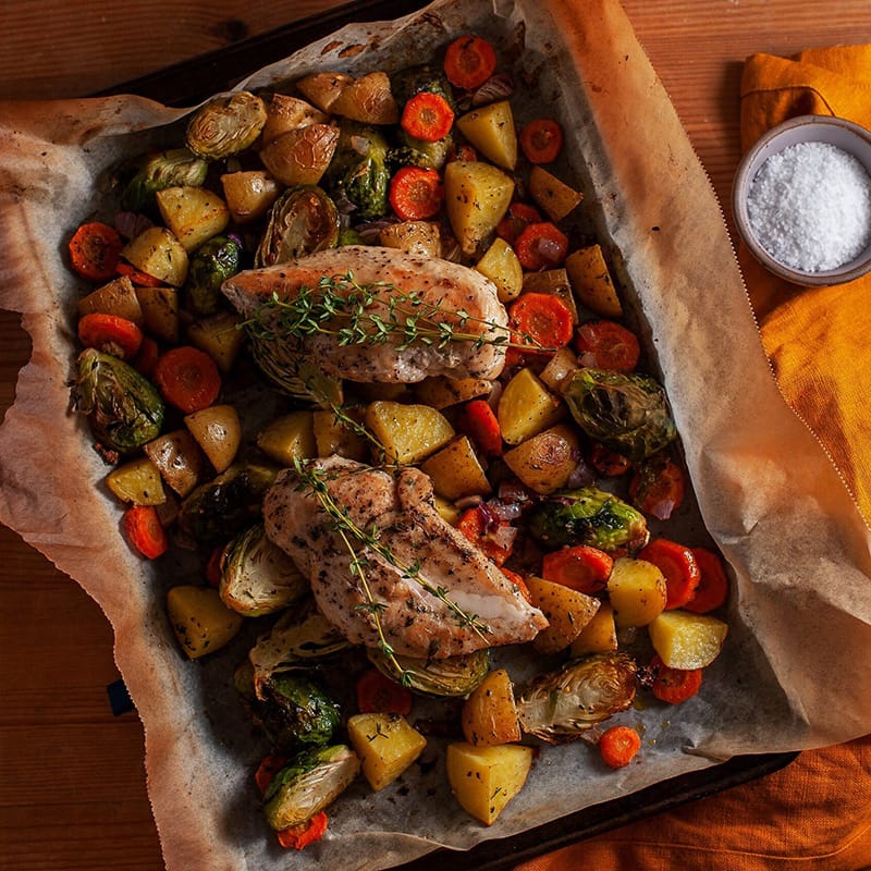 Roast chicken with vegetables on a baking sheet, seasoned and ready to serve