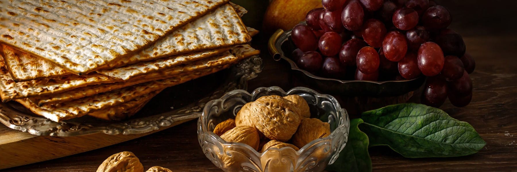 Traditional jewish passover holiday ingredients on a table with matzah, grapes, karpas, and nuts.