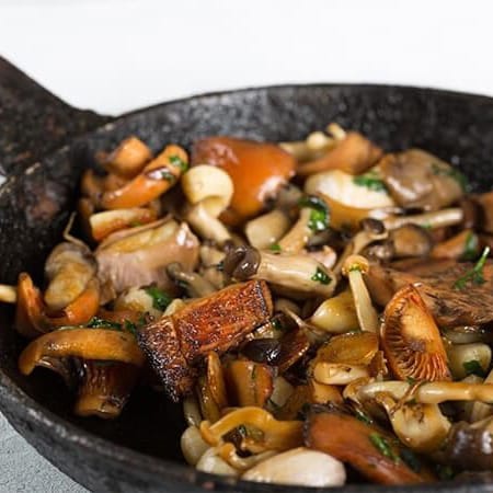 Pan of sautéed mushrooms with herbs and seasoning.