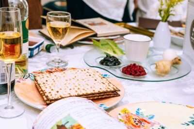 Passover table setting with a traditional seder plate, symbolic meal, wine, and matzah. People are seated for Passover Seder.