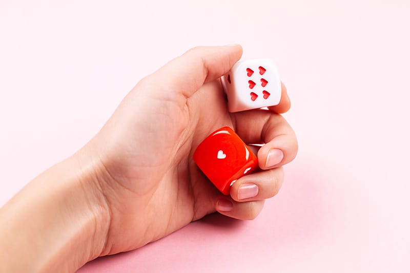 Hand holding two dice with heart symbols, suggesting a playful or loving theme