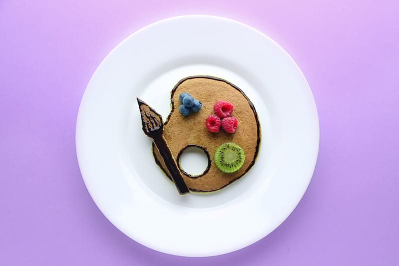 Pancake with fresh berries and kiwi on a white plate, artistic presentation