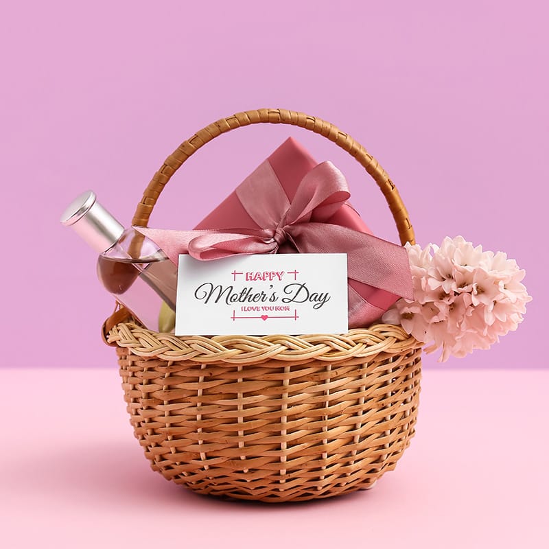 Mother's Day gift basket with wine and pink bow on a pink background