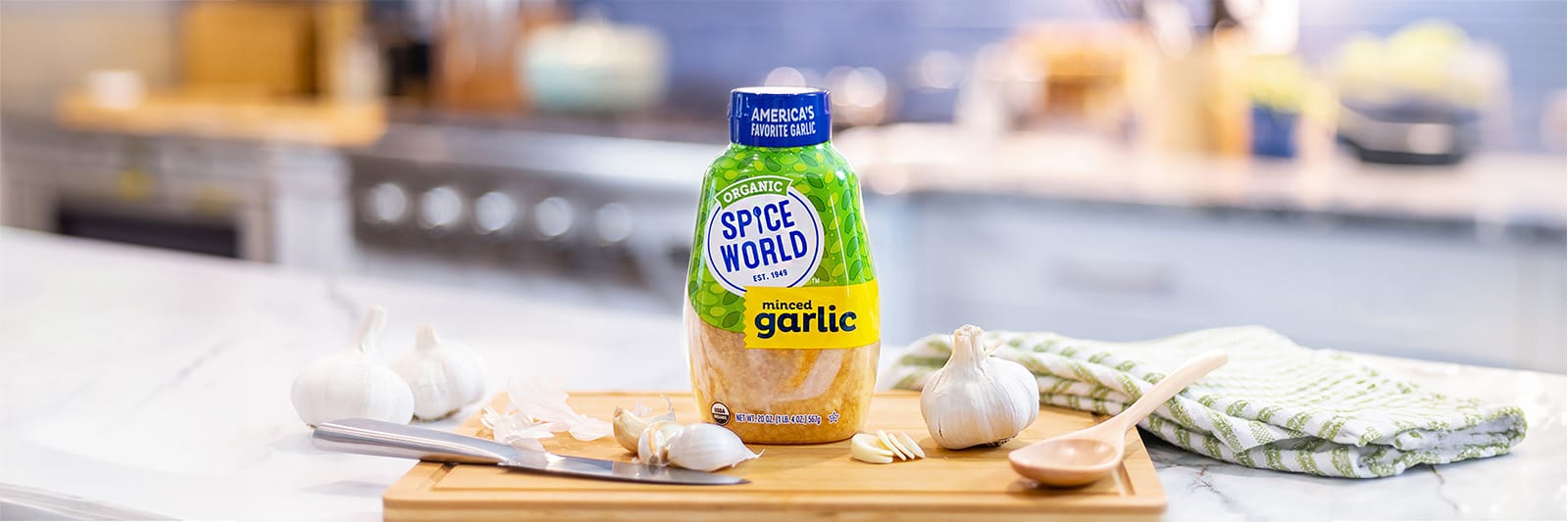 Close up of Spice World Organic Squeezable garlic on a brown cutting board surrounded by fresh garlic cloves on a kitchen background