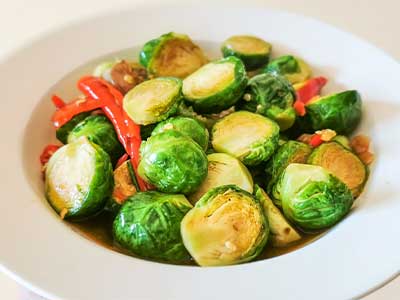 Plate of roasted Brussels sprouts with red peppers, served as a healthy meal