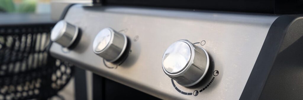 Close-up of gas grill knobs, ready for outdoor cooking