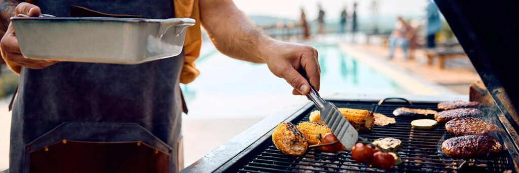 Man grilling assorted tasty foods by a poolside, signifying enjoyable outdoor cooking