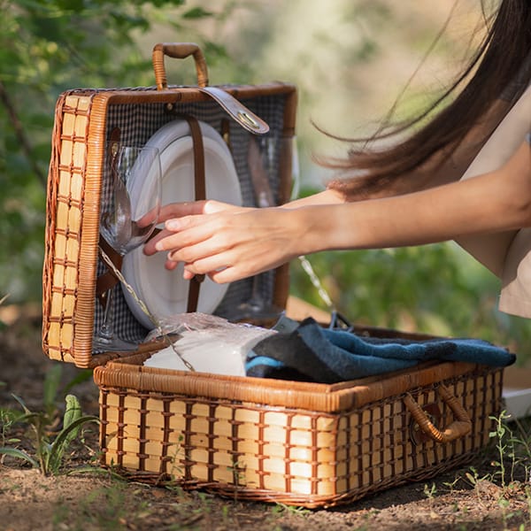 Woman packing picnic basket with wine glasses for summer outdoor dining and picnics.