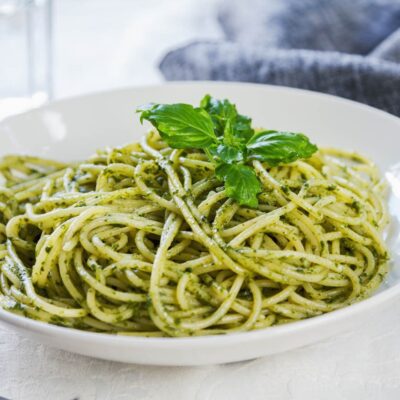 Plate of pesto pasta garnished with fresh basil