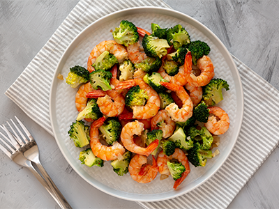 A dish of shrimp and broccoli served on a white plate, representing a healthy meal choice