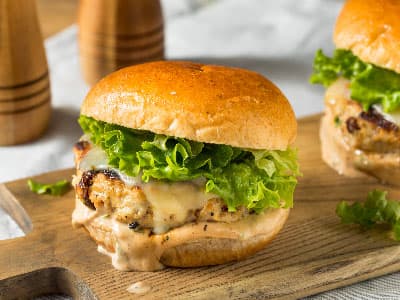 Delicious chicken burger with lettuce on a wooden board