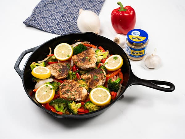 Pan-seared chicken with broccoli, bell peppers, and lemon slices in a skillet, ready to serve