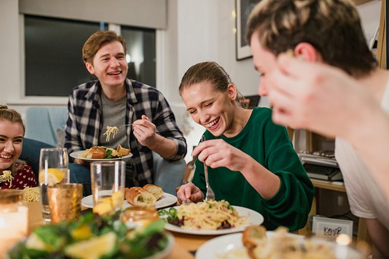 Group of friends laughing and enjoying a meal together at a dinner table