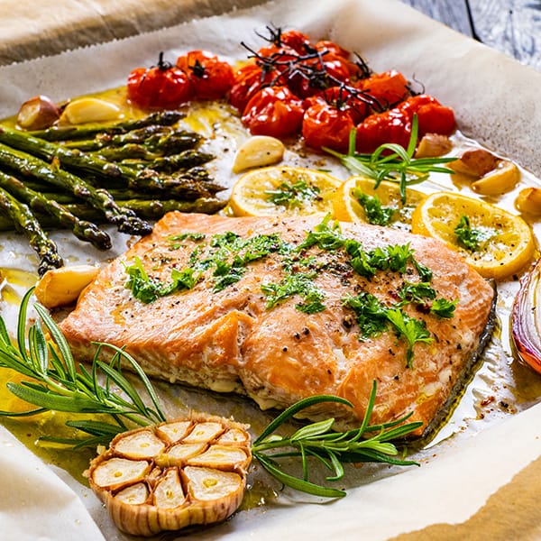 Roasted salmon with asparagus, tomatoes, and herbs on parchment paper