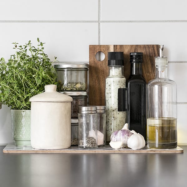Kitchen shelf with cooking ingredients like oils, spices, and fresh herbs
