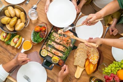 Overhead view of a shared meal with hands reaching for food.