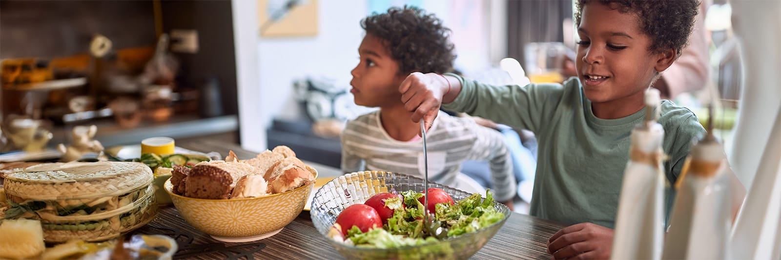 Two children preparing salad at home, enjoying a variety of healthy foods