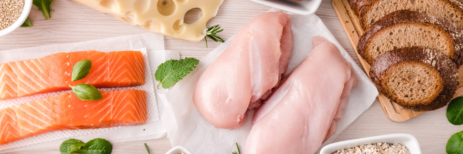 Assorted fresh ingredients including salmon, chicken, cheese, and bread for preparing healthy meals
