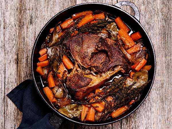 Roasted chicken with carrots and herbs in a cooking pot
