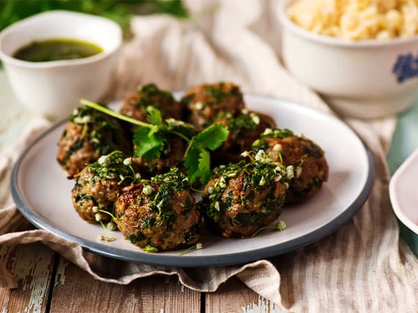 Plate of fresh herb falafels with a side of green sauce
