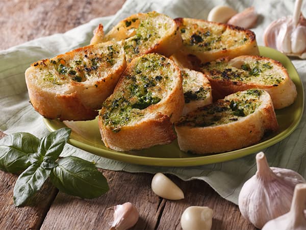 Slices of garlic bread with herbs on a green plate, suggesting a tasty appetizer