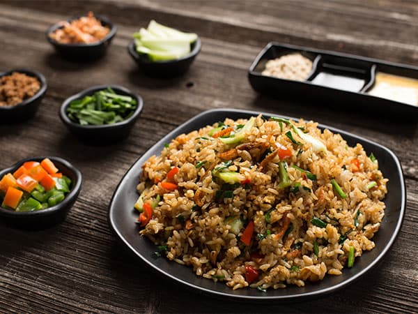 Plate of vegetable fried rice with side dishes on a wooden table