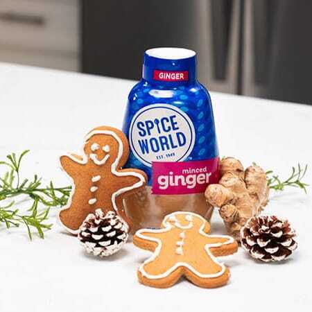 Gingerbread cookies with a bottle of minced ginger and fresh ginger roots on a kitchen counter