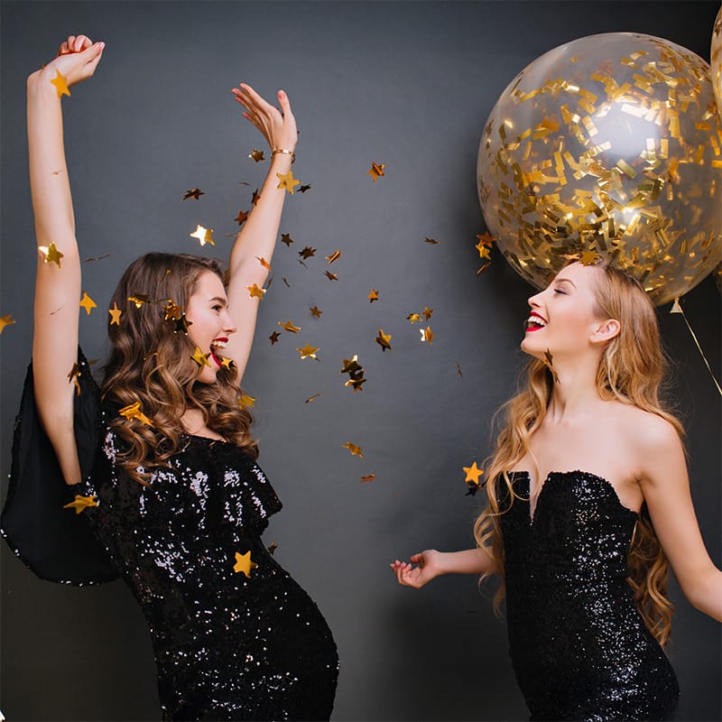 Friends celebrating at a party with confetti and balloons, creating a festive atmosphere for enjoying delicious food