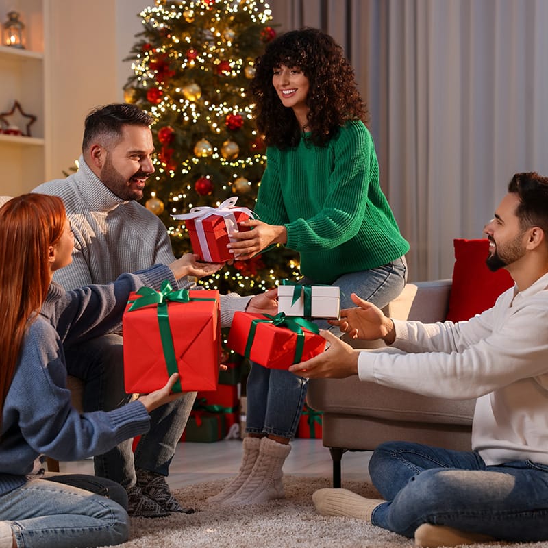 A cozy gathering of friends sharing holiday gifts by a decorated Christmas tree, celebrating the festive spirit