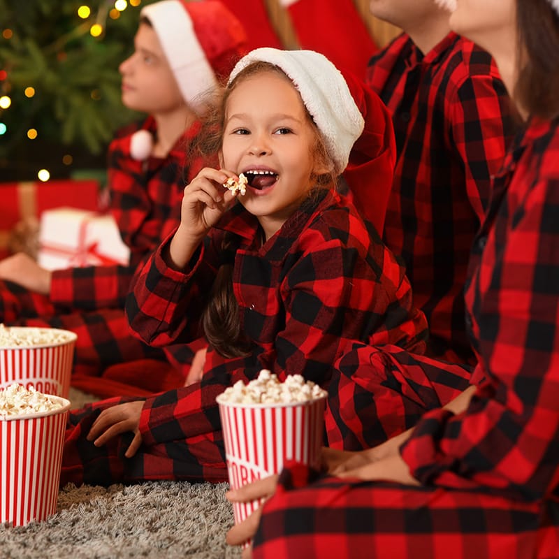 Child enjoying popcorn with family during a cozy holiday movie night celebration