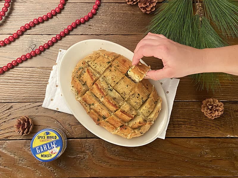 A hand reaches for a flavorful, baked garlic bread on a festive table setting, inviting sharing and enjoyment