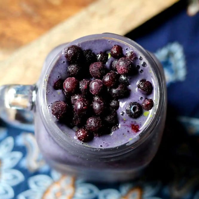 Mason jar filled with a creamy blueberry smoothie topped with fresh berries, perfect for a refreshing snack