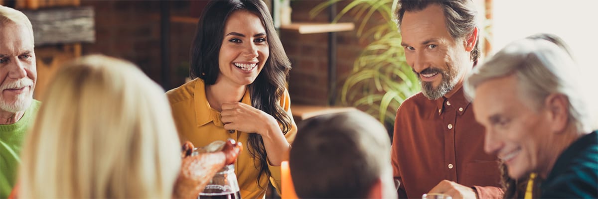 Group of friends enjoying a meal together, sharing smiles and laughter around a dining table