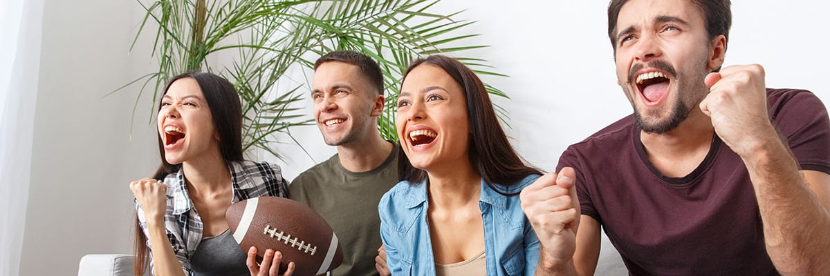 Group of friends joyfully celebrating while enjoying snacks during a football game