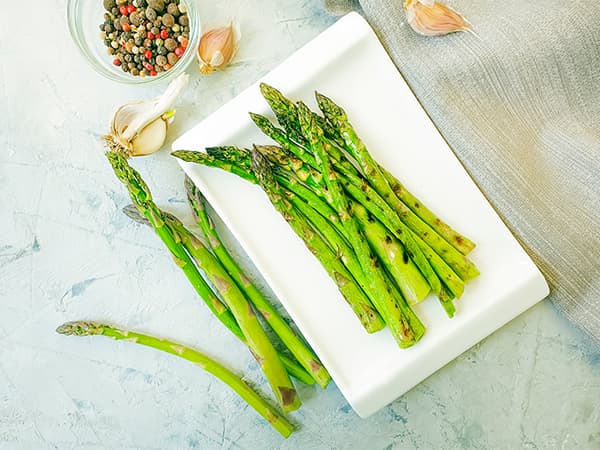 Grilled asparagus on a plate with spices and garlic, ready to enhance a delicious meal
