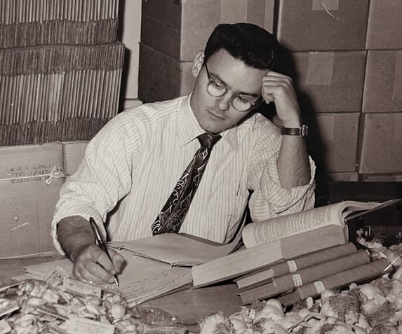 A man reviewing notes and books about food, focusing on culinary research surrounded by ingredients