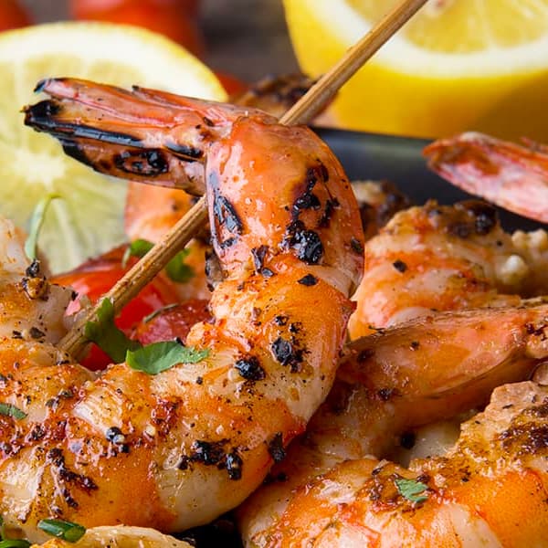 Grilled shrimp garnished with herbs and lemon, served as a delicious seafood dish