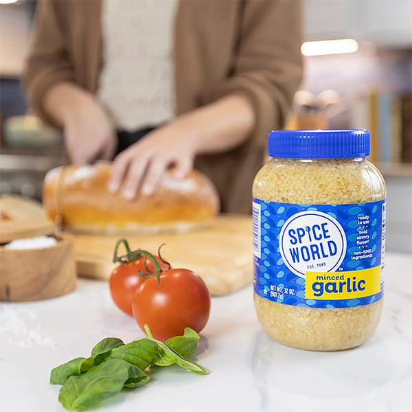 A jar of minced garlic with fresh tomatoes and basil, highlighting ingredients for a delicious recipe