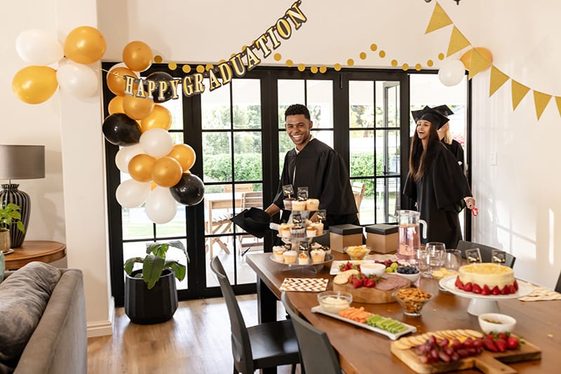 Graduation celebration with joyful guests and a table filled with delicious food and treats
