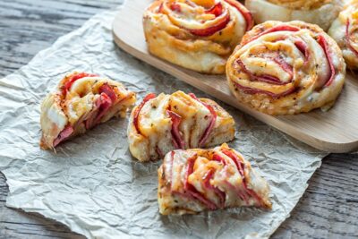 Freshly baked roll-ups filled with cheese and ham, served on a wooden board for a delightful snack