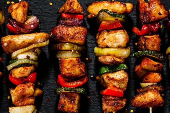 Grilled chicken and vegetable skewers on a dark platter, perfect for a tasty meal or summer barbecue