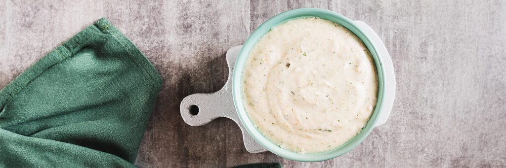 Creamy dip in a turquoise bowl, served with a green cloth, perfect for sharing or enjoying as a snack