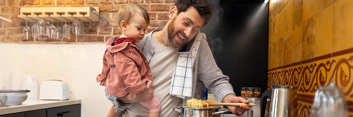 A joyful moment in the kitchen with a parent cooking pasta and a child watching curiously